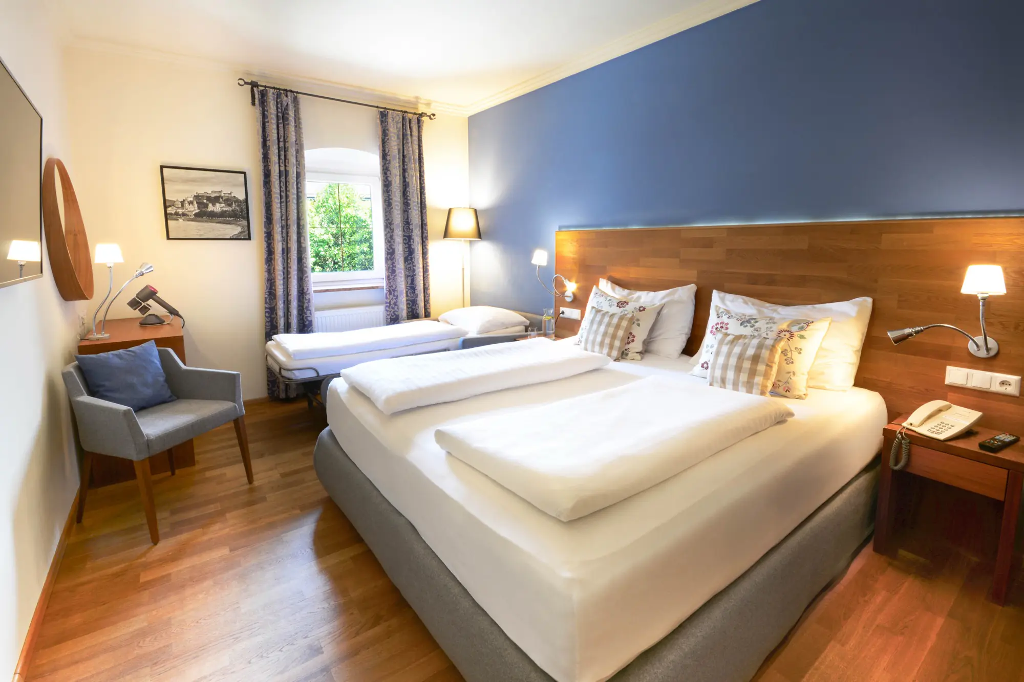 Familienzimmer Superior im Hotel Kaiserhof Anif – Doppelbett mit Zusatzbett und Blick in den Garten